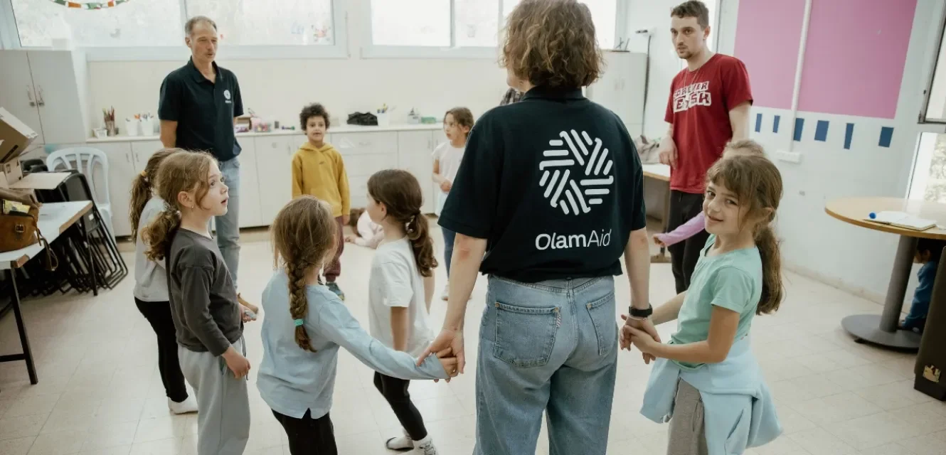 Eine Frau hält Kinder im Kreis an den Händen