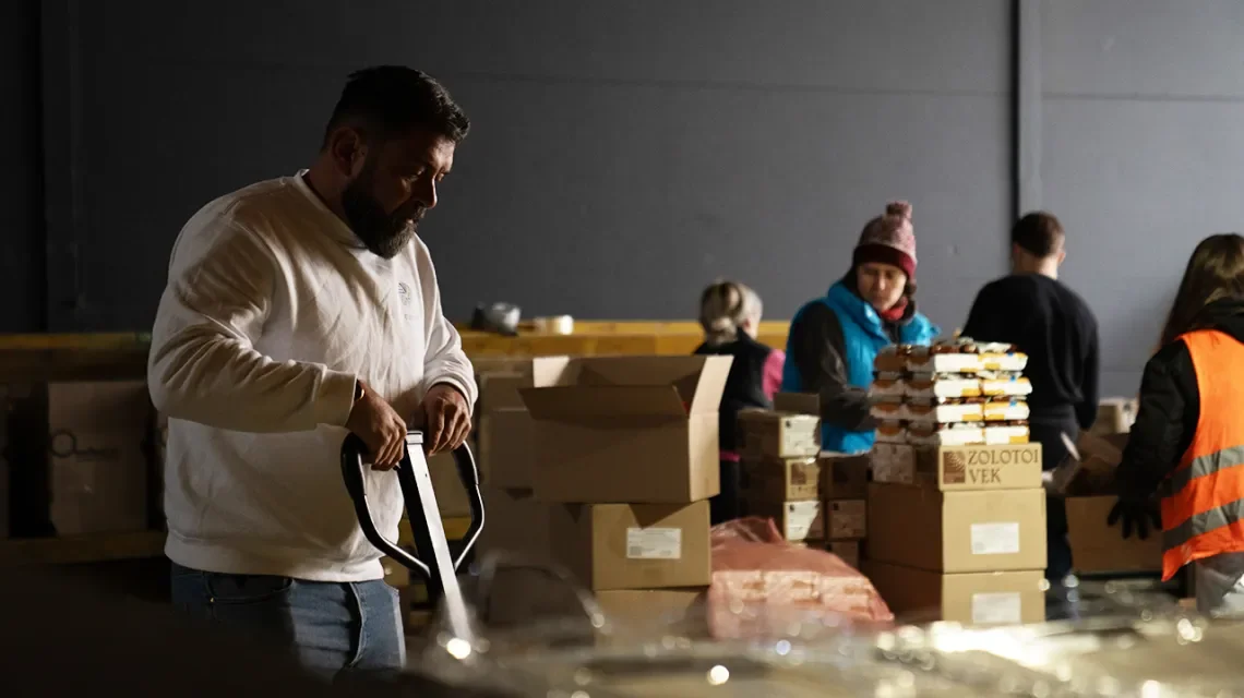 Ein Mann in einem Lagerraum verlädt Hilfsgüter